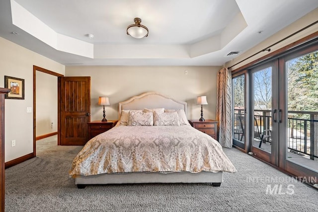 carpeted bedroom with access to exterior, baseboards, and a tray ceiling