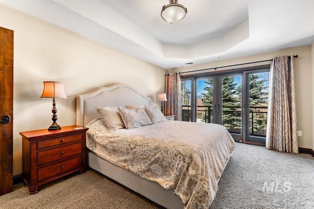 carpeted bedroom featuring access to outside, a tray ceiling, and baseboards