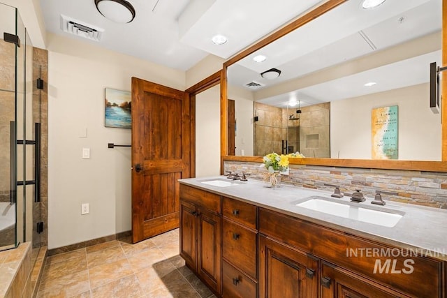 bathroom featuring a shower stall, tasteful backsplash, baseboards, double vanity, and recessed lighting