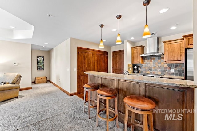 kitchen with wall chimney exhaust hood, carpet, baseboards, stainless steel fridge, and a skylight