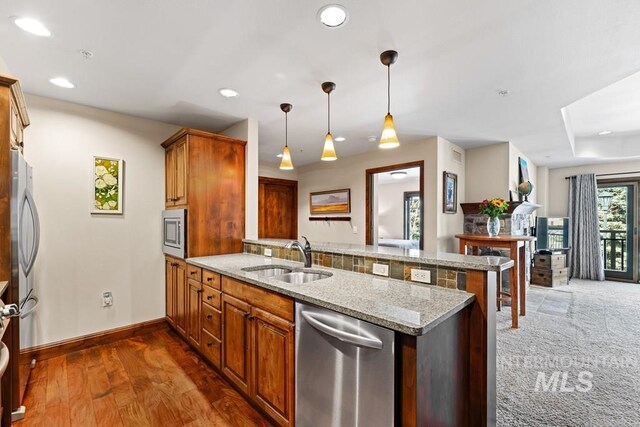 kitchen featuring a sink, stainless steel appliances, a peninsula, recessed lighting, and baseboards