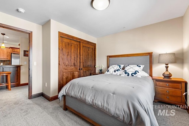 bedroom featuring light colored carpet, refrigerator, a closet, and baseboards