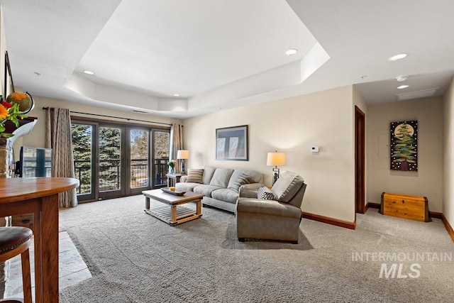 carpeted living area featuring a raised ceiling, baseboards, and recessed lighting