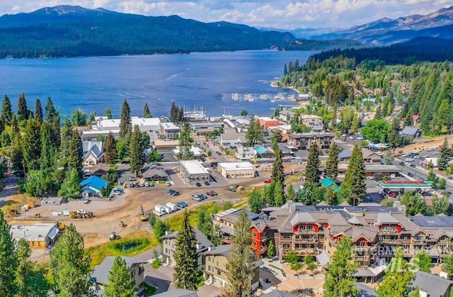 drone / aerial view of a heavily wooded area and a water and mountain view