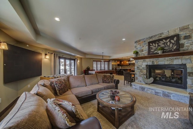 carpeted living area with a stone fireplace and recessed lighting
