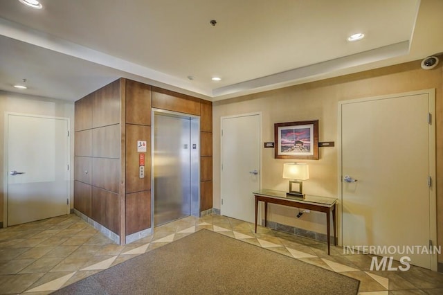 foyer entrance featuring elevator, a tray ceiling, and recessed lighting