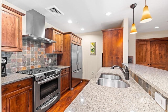 kitchen featuring appliances with stainless steel finishes, wall chimney exhaust hood, a sink, light stone countertops, and tasteful backsplash