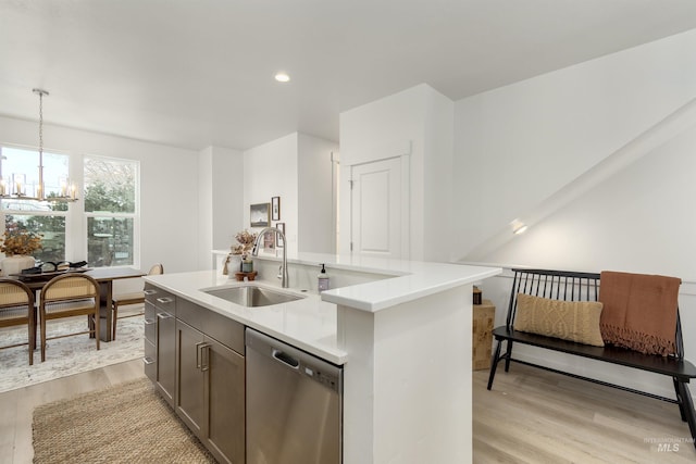 kitchen featuring light hardwood / wood-style flooring, sink, dishwasher, hanging light fixtures, and a kitchen island with sink