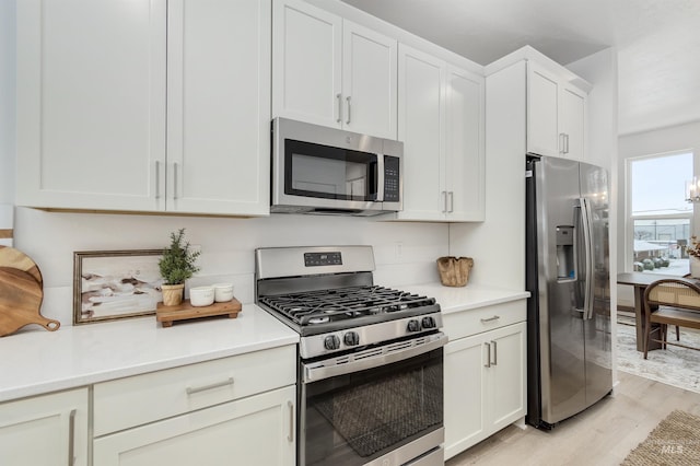 kitchen with light hardwood / wood-style floors, stainless steel appliances, and white cabinets