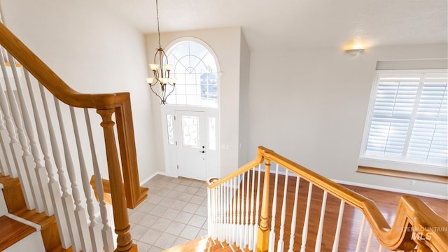 foyer featuring a chandelier, stairway, and baseboards