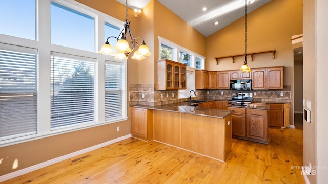 kitchen featuring black microwave, a peninsula, visible vents, stainless steel electric range oven, and brown cabinetry