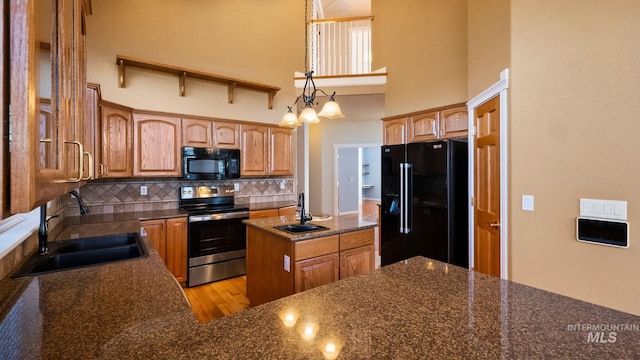 kitchen featuring black appliances, a high ceiling, backsplash, and a sink