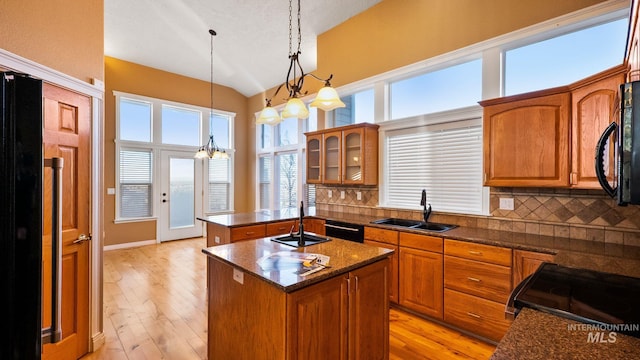 kitchen with decorative backsplash, brown cabinets, a peninsula, black appliances, and a sink