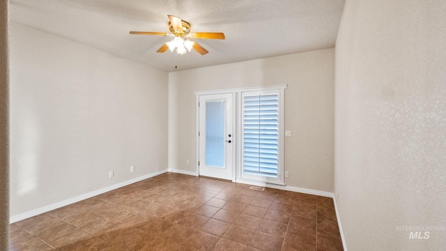 tiled spare room featuring a ceiling fan, visible vents, and baseboards