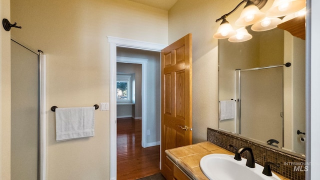 full bathroom with a shower with door, baseboards, wood finished floors, and vanity