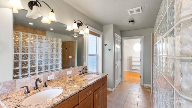 bathroom featuring a textured ceiling, visible vents, a sink, and tile patterned floors