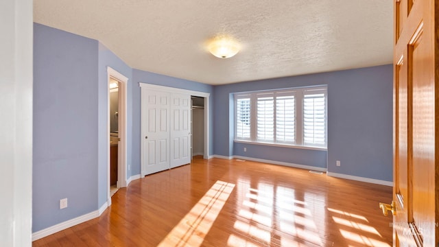 unfurnished bedroom with a closet, visible vents, baseboards, and wood finished floors