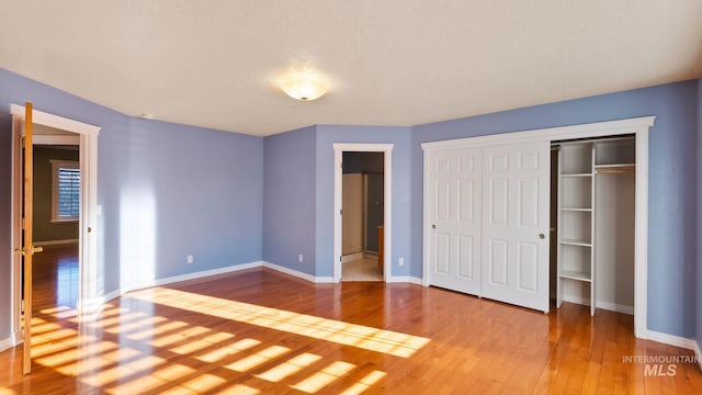 unfurnished bedroom with a closet, baseboards, and hardwood / wood-style floors