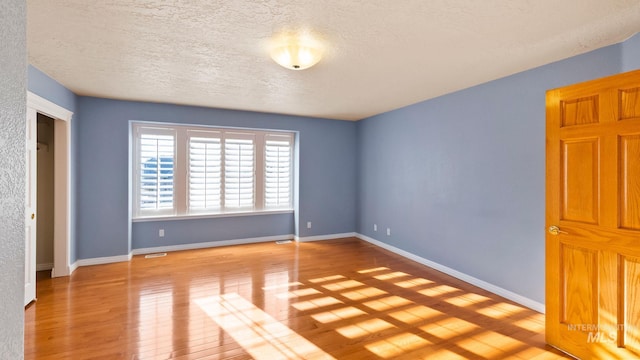 unfurnished bedroom featuring a textured ceiling, wood-type flooring, visible vents, and baseboards