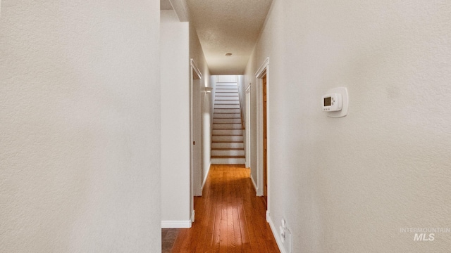 hall featuring stairway, wood-type flooring, and baseboards