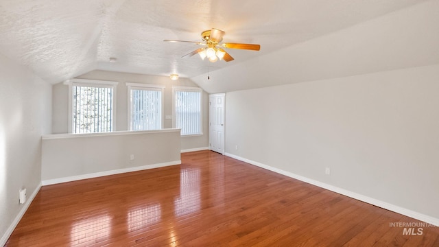 additional living space with a textured ceiling, ceiling fan, baseboards, vaulted ceiling, and hardwood / wood-style floors