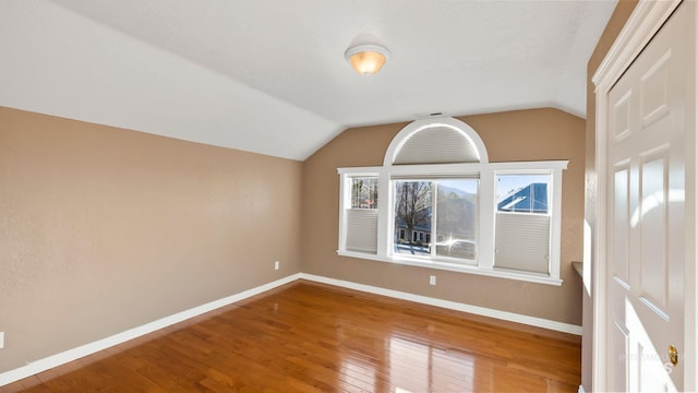 bonus room featuring lofted ceiling, hardwood / wood-style flooring, and baseboards