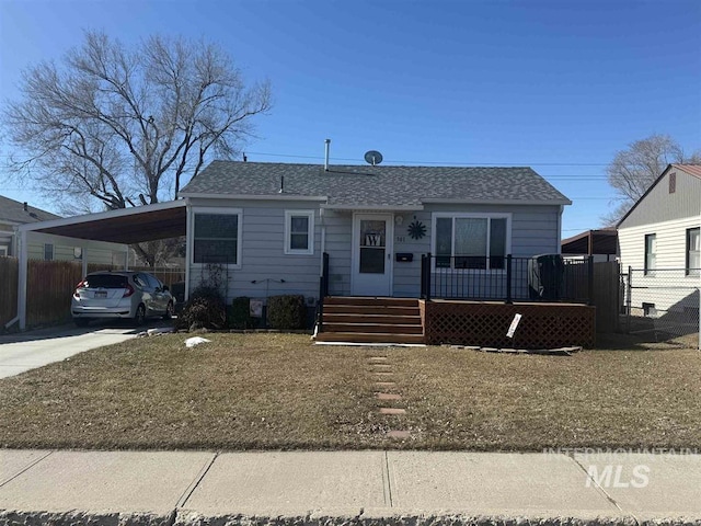 view of front facade featuring concrete driveway, an attached carport, roof with shingles, and fence