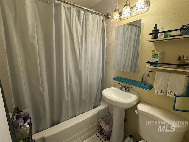 bathroom with a textured wall, shower / bath combo, and toilet