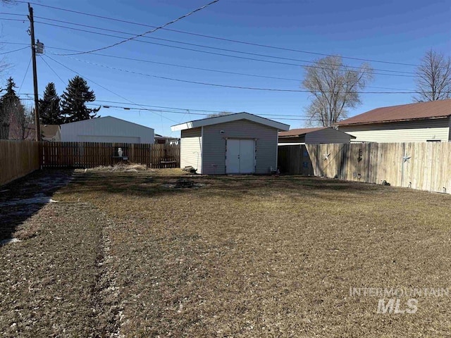 view of yard featuring a storage shed, a fenced backyard, and an outdoor structure