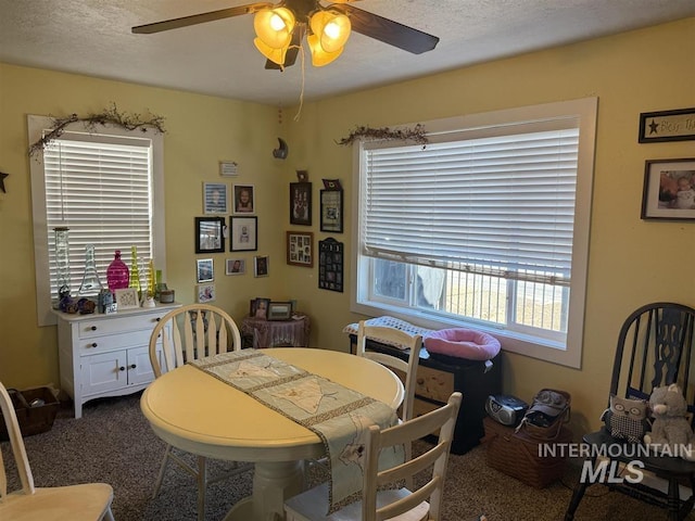 carpeted dining space with a textured ceiling and ceiling fan