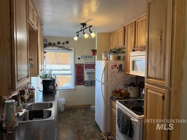 kitchen with white appliances, a sink, baseboards, brown cabinetry, and dark countertops