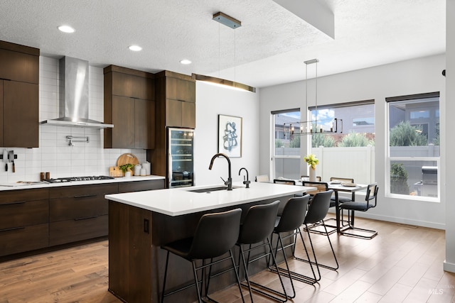 4213 E Divide Pass St, Meridian, ID 83642 - kitchen featuring wall chimney exhaust hood, modern cabinets, light countertops, beverage cooler, and a textured ceiling