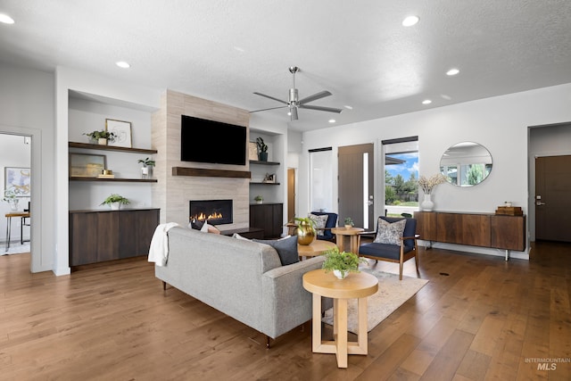 4213 E Divide Pass St, Meridian, ID 83642 - living room with wood finished floors, a ceiling fan, a large fireplace, recessed lighting, and a textured ceiling