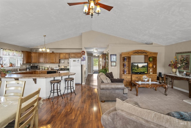 642 Oak St, Twin Falls, ID 83301 - living room with vaulted ceiling, dark wood finished floors, a chandelier, a ceiling fan, and baseboards