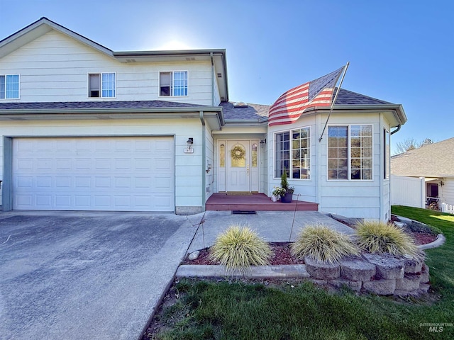 traditional-style house featuring an attached garage, roof with shingles, and concrete driveway