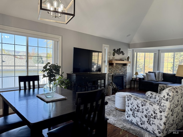 dining area with a chandelier, a wealth of natural light, vaulted ceiling, and wood finished floors