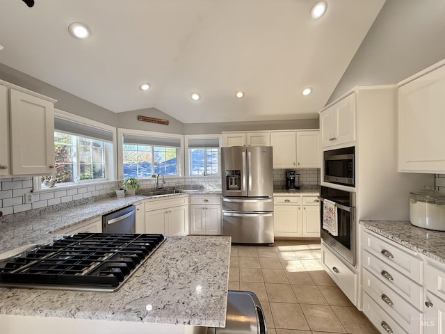 kitchen with a sink, backsplash, light tile patterned floors, vaulted ceiling, and stainless steel appliances