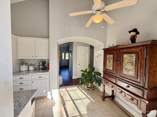 interior space with arched walkways, light tile patterned floors, a high ceiling, and ceiling fan