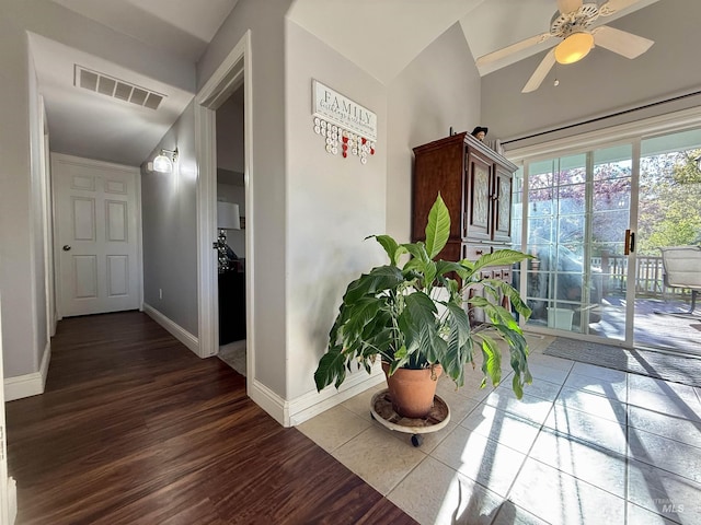 hallway featuring baseboards, visible vents, wood finished floors, and lofted ceiling