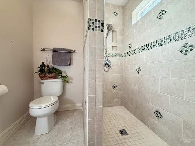 full bathroom featuring baseboards, tile patterned flooring, toilet, and tiled shower