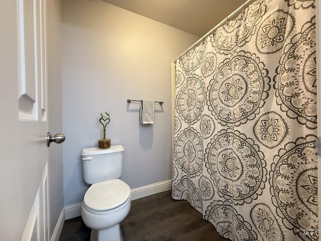 bathroom featuring toilet, baseboards, wood finished floors, and a shower with curtain