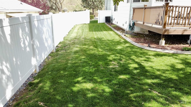 view of yard with a deck, central AC, and fence
