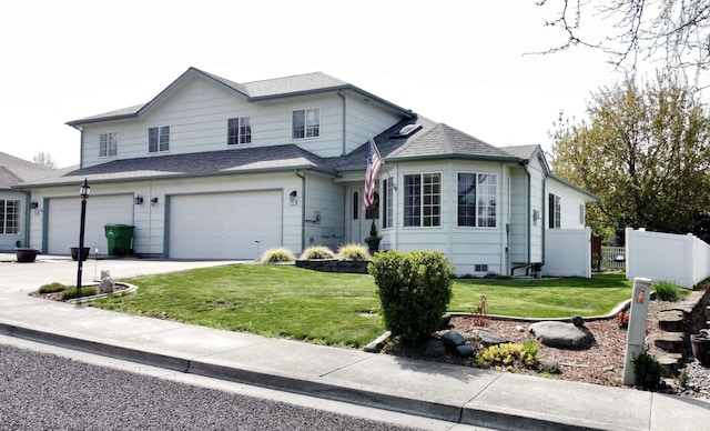 traditional-style home featuring a garage, fence, a front yard, a shingled roof, and driveway