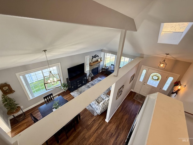 living area with dark wood-style flooring, baseboards, an inviting chandelier, and lofted ceiling with skylight