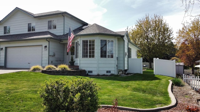 traditional-style house featuring fence, roof with shingles, a front lawn, and a garage