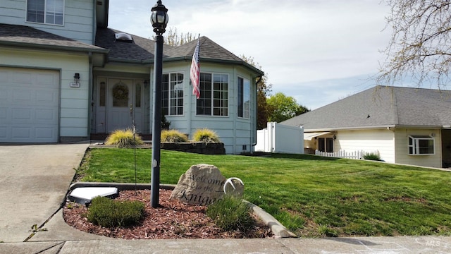 view of side of property featuring fence, roof with shingles, a garage, a lawn, and driveway