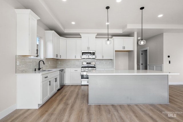 kitchen featuring backsplash, a kitchen island, light wood-type flooring, stainless steel appliances, and a sink