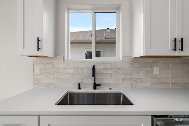 kitchen featuring decorative backsplash, white cabinetry, light countertops, and a sink