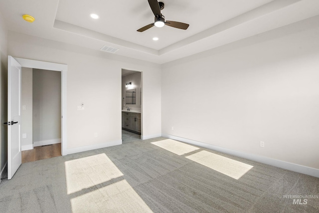 unfurnished bedroom with recessed lighting, visible vents, a raised ceiling, and baseboards