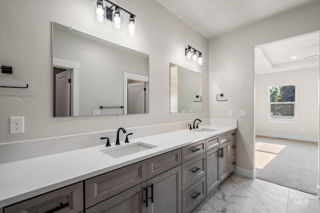 full bathroom with a sink, baseboards, marble finish floor, and double vanity